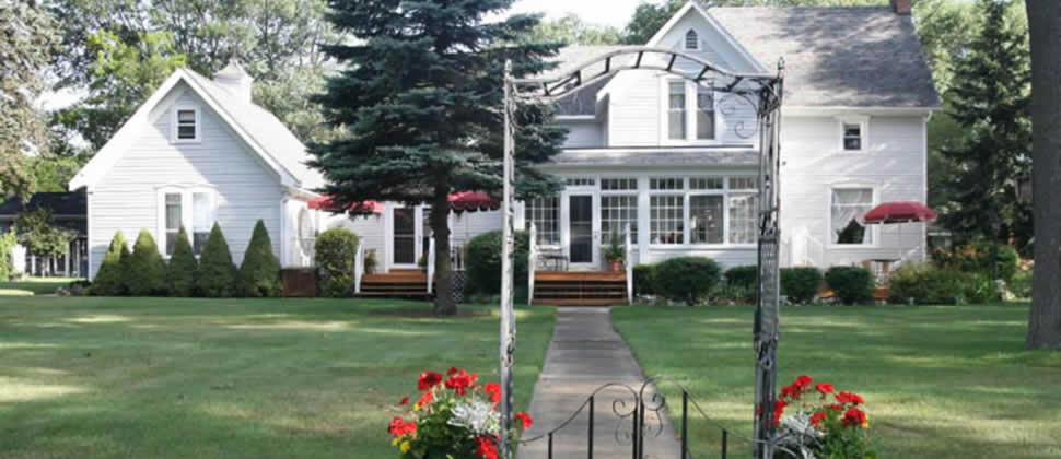 view of the white clapboard inn from the street, view of the lawn and inn through an iron gate and archway