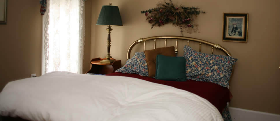 Beige room with brass bed, with white covers and floral pillow covers