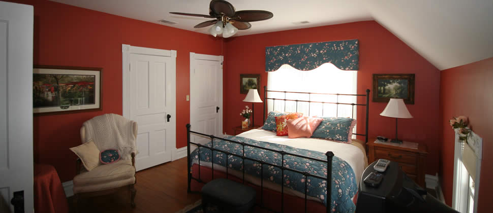 Bedroom with red walls and bed with window behind bed with blue curtins.