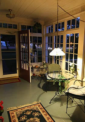 porch in the evening iluminated by hanging light abobe class and iron table with two chairs